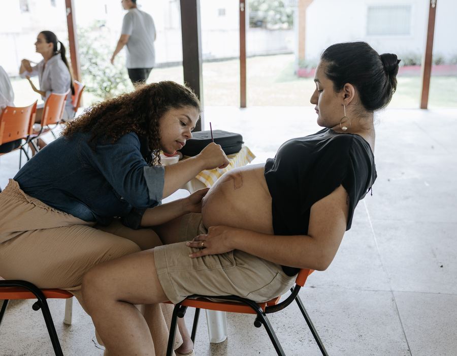 Arte gestacional sendo pintada na barriga de uma gestante